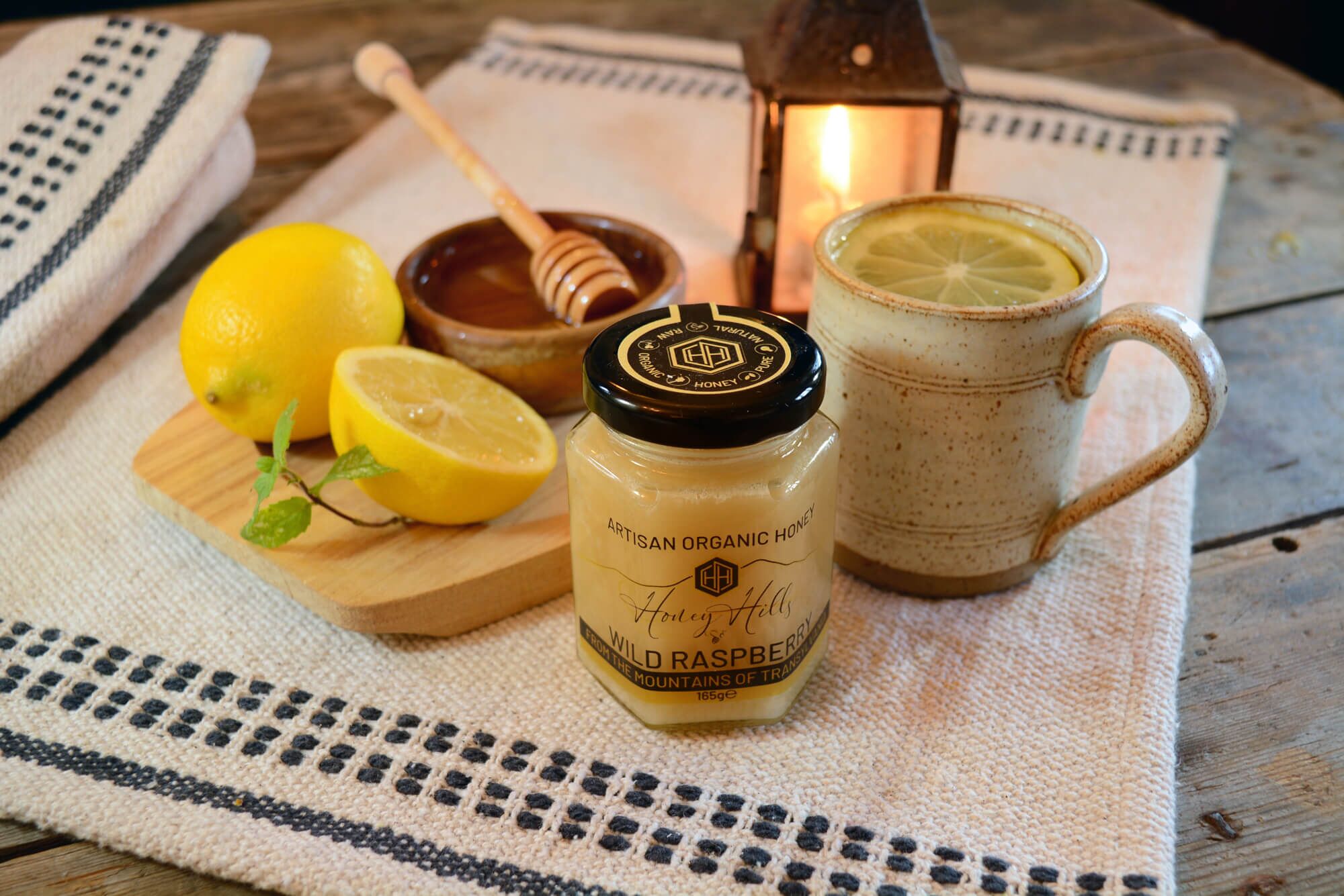 artisan-organic-honey-wild-raspberry - Honey Hills - Online artisan shop with delicious, rare raw mountain honey varieties Jar of artisan organic wild raspberry honey with fresh lemons and a cup of lemon tea.