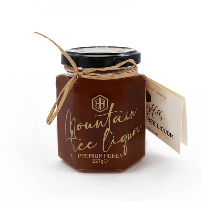 MountainTreeLiquor - Honey Hills - Online artisan shop with delicious, rare raw mountain honey varieties Premium Mountain Tree Liquor Honey in a decorative jar, showcasing its rich color and unique flavor, made from honeydews of fir, oak, and beech trees.